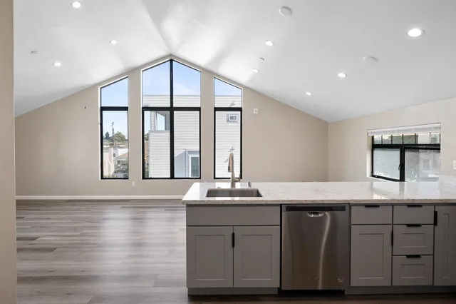 a kitchen with kitchen island granite countertop a sink and a large window