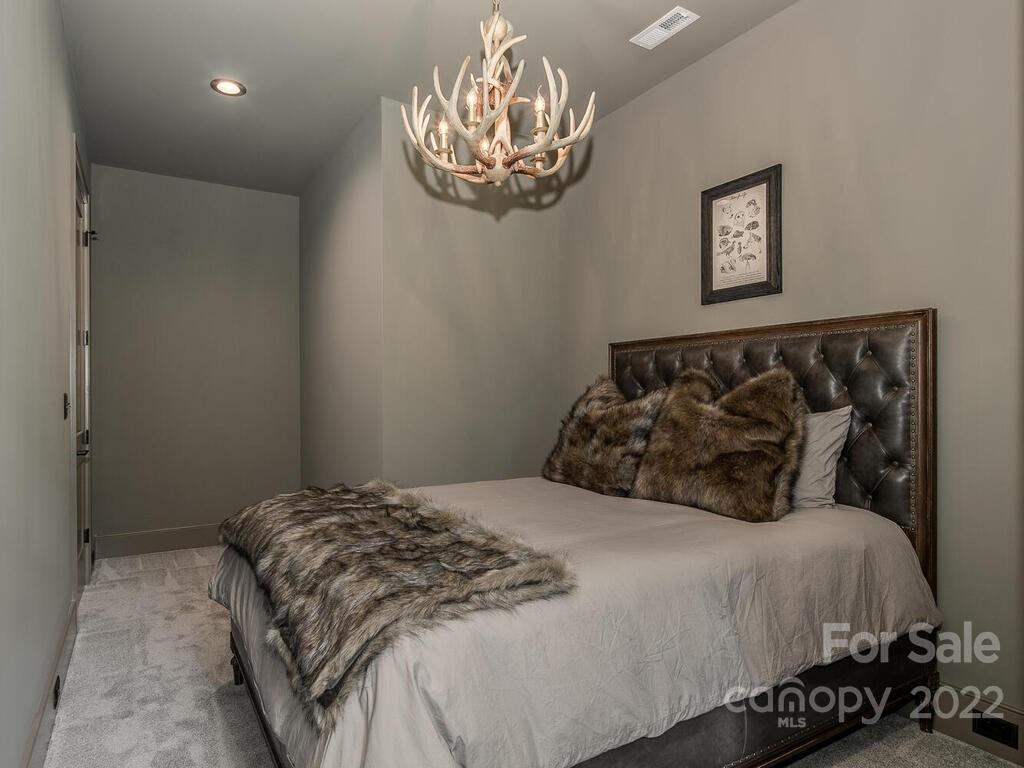 13601 Girl Scout Road Charlotte, NC 28278 - Photo 37 of 45 a bedroom with a bed and a chandelier