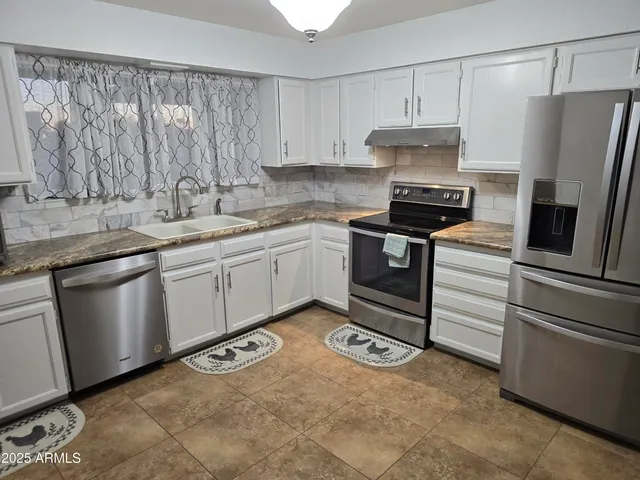 a kitchen with stainless steel appliances granite countertop a sink stove and refrigerator