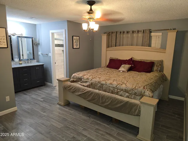 a bedroom with a large bed a chandelier and dresser