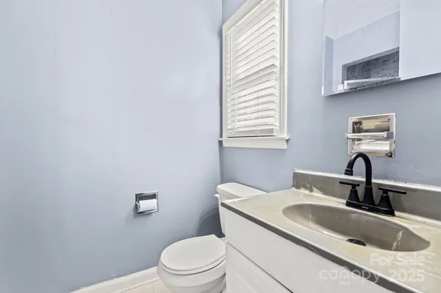 a bathroom with a granite countertop sink toilet and mirror