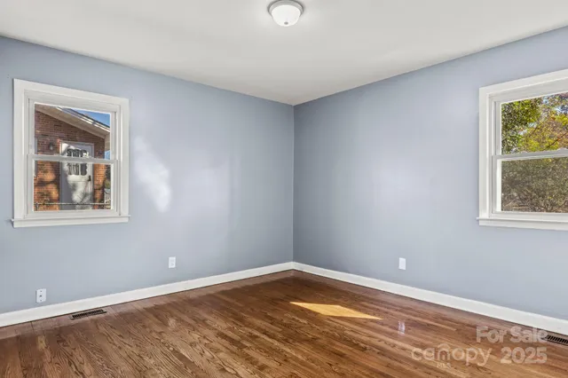 a view of empty room with window and wooden floor