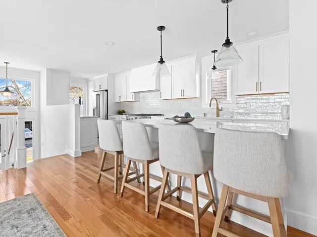 a kitchen with stainless steel appliances kitchen island granite countertop a dining table chairs and white cabinets