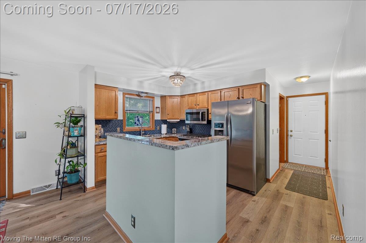 40162 Alden Road Belleville, MI 48111 - Photo 11 of 67 Modern kitchen featuring wood cabinetry, stainless steel appliances, a breakfast bar with a granite-style countertop, and wood-finish flooring