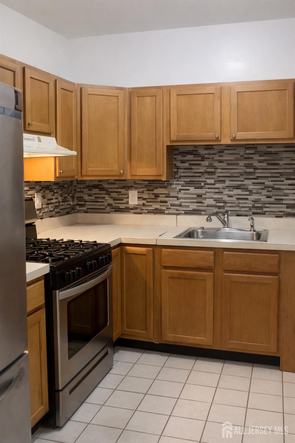 132 Remsen Avenue New Brunswick, NJ 08901 - Photo 6 of 11 a kitchen with granite countertop a sink stove and cabinets