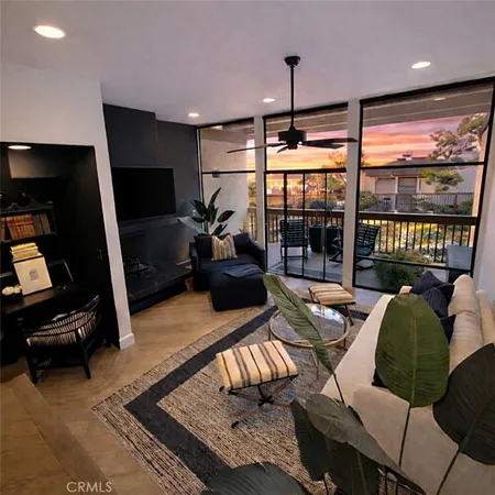 a living room with furniture a flat screen tv and floor to ceiling window