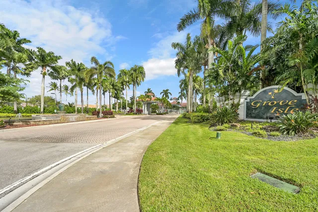 a palm tree sitting in front of a house with a yard and trees