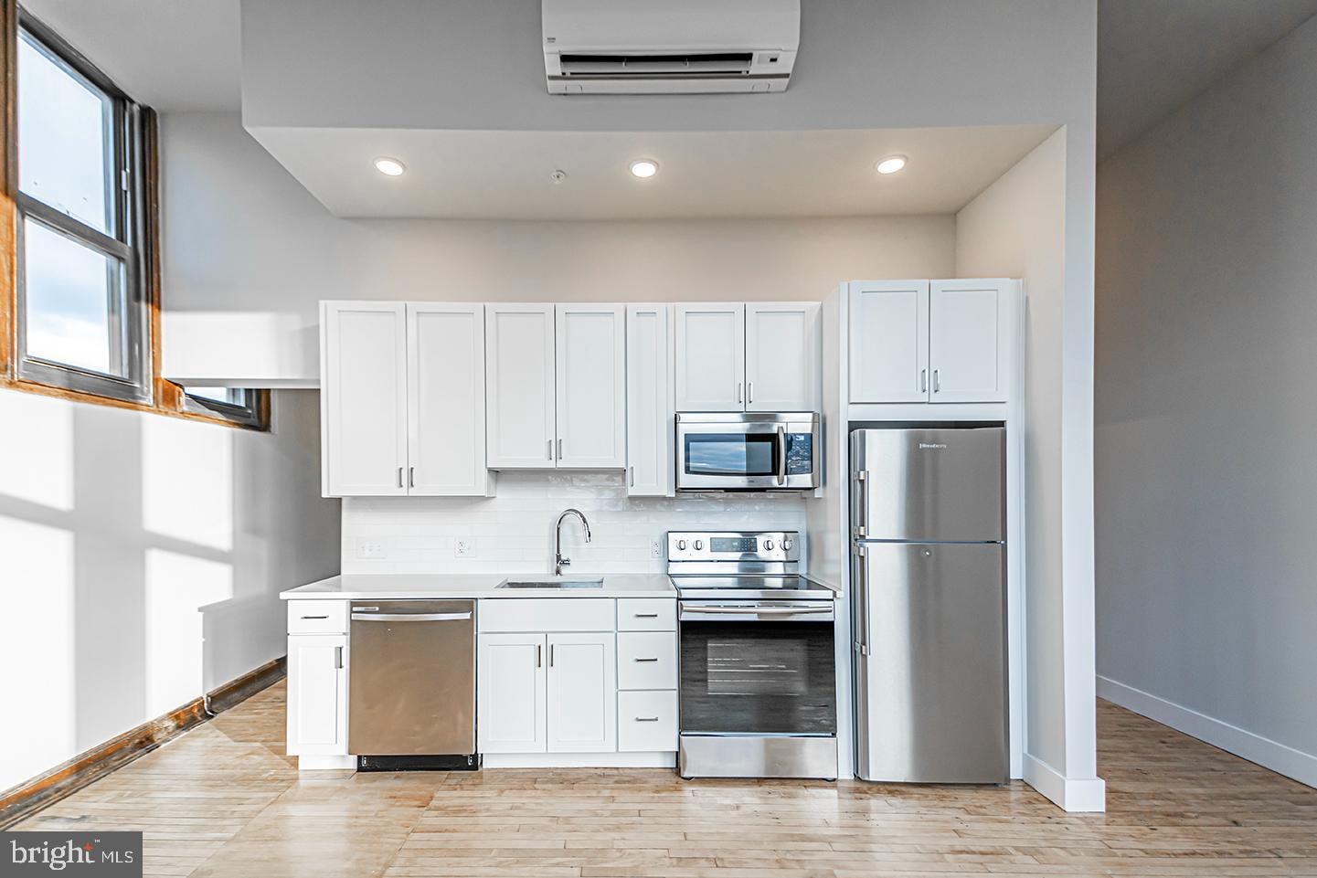 a kitchen with stainless steel appliances a refrigerator a stove a sink and white cabinets