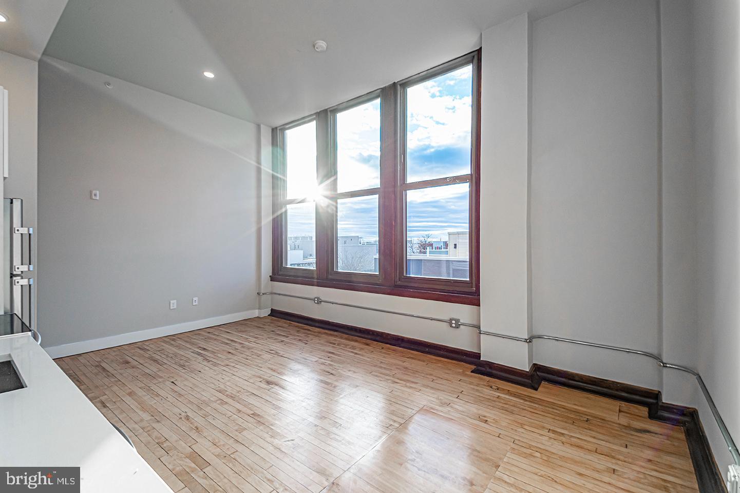 1300 South 19th Street, Unit 316 Philadelphia, PA 19146 - Photo 4 of 19 an empty room with wooden floor and windows