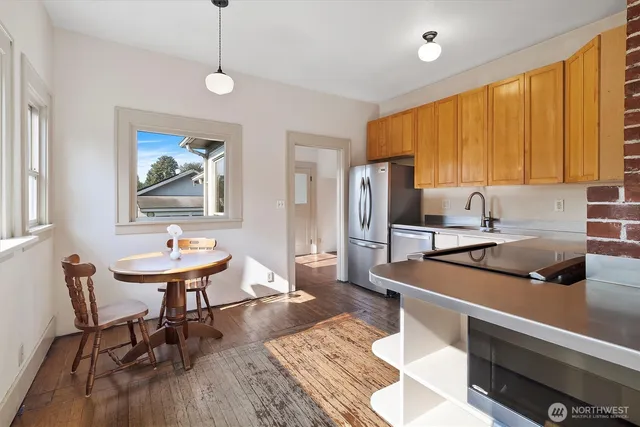 a kitchen with stainless steel appliances a dining table chairs and a refrigerator