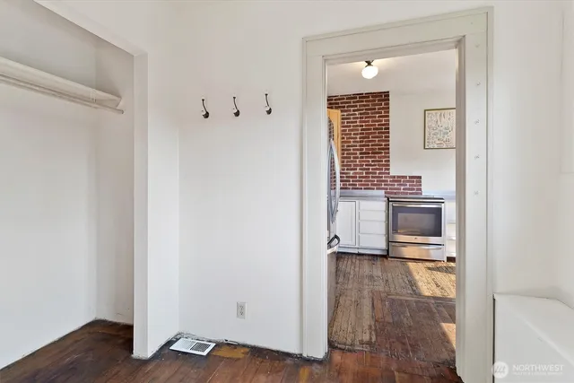 a view of a hallway with wooden floor and a bathroom