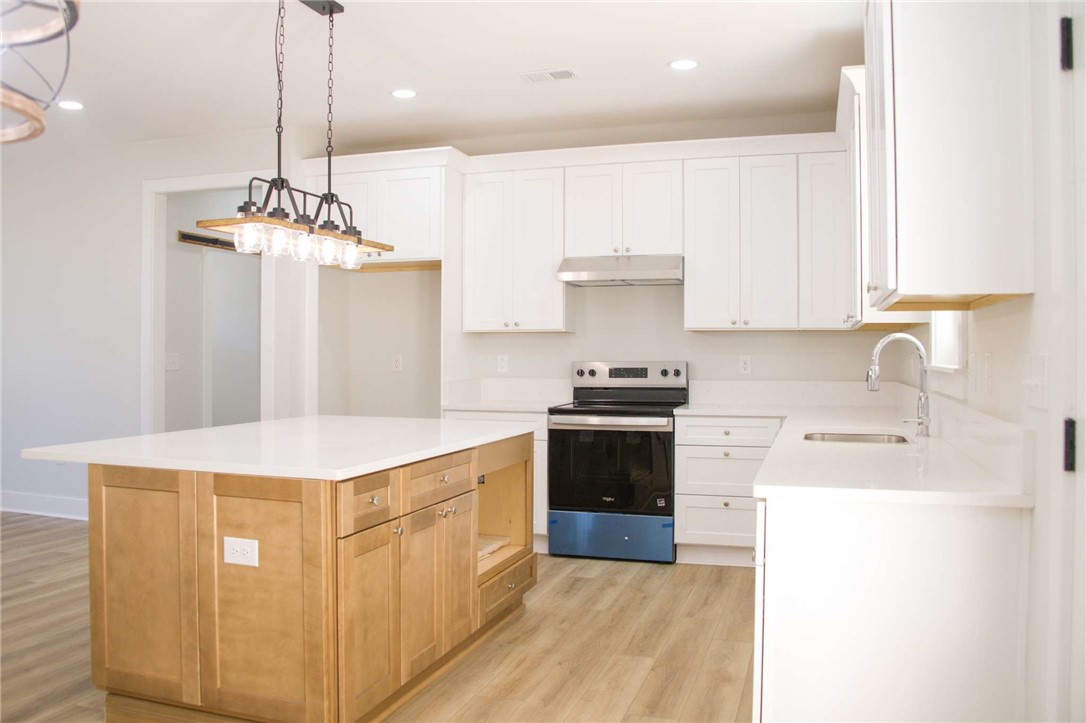2515 Highway 29 Anderson, SC 29621 - Photo 11 of 38 A contemporary kitchen features bright white cabinetry and a contrasting wooden island, offering both style and functionality.