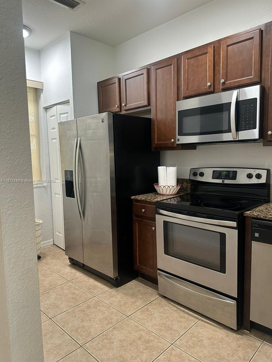 8936 Southwest 18th Street, Unit 8936 Miramar, FL 33025 - Photo 5 of 10 a kitchen with stainless steel appliances granite countertop a refrigerator stove and microwave