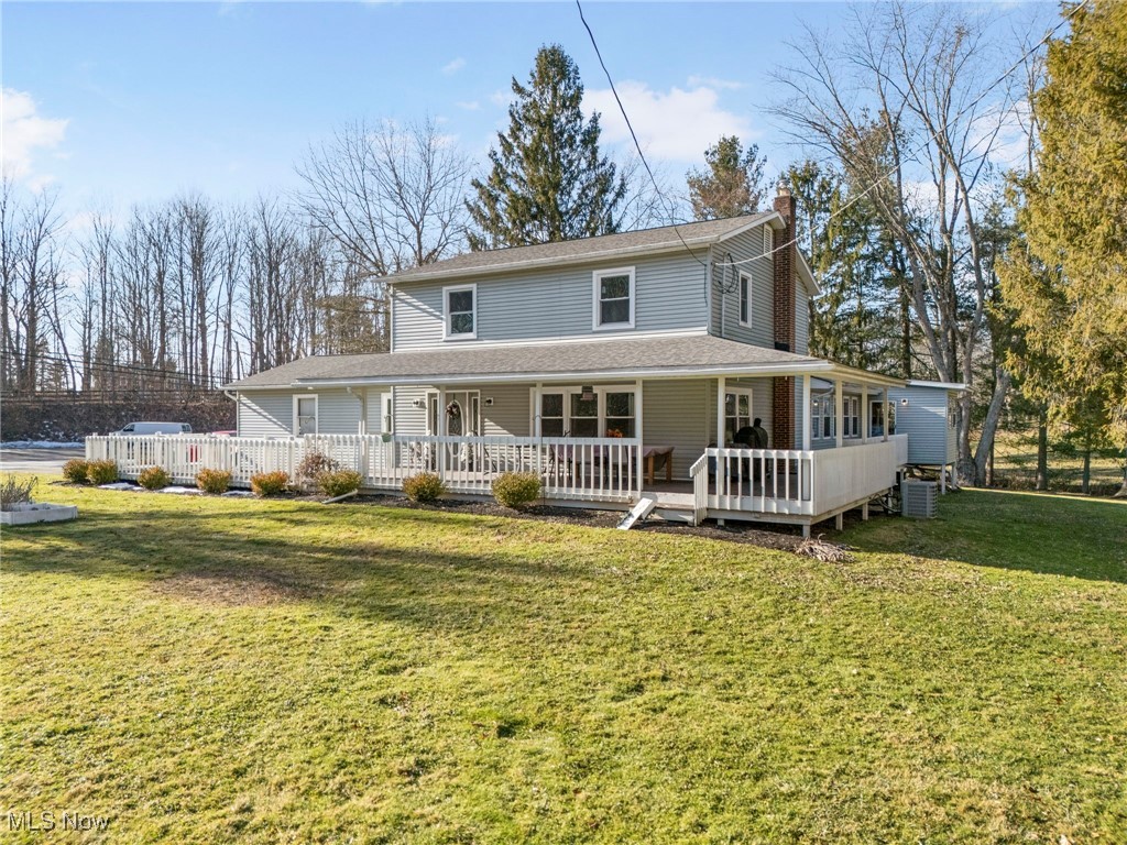 View of front of property with a front lawn, a chimney, covered porch, and roof with shingles