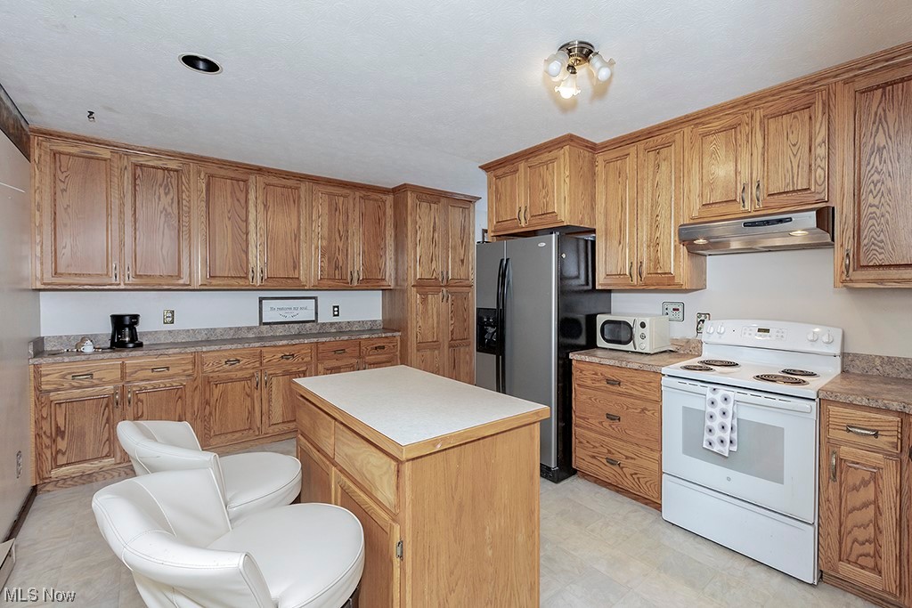 39102 Chestnut Ridge Road Elyria, OH 44035 - Photo 17 of 44 Kitchen featuring a kitchen island, white appliances, and light tile flooring