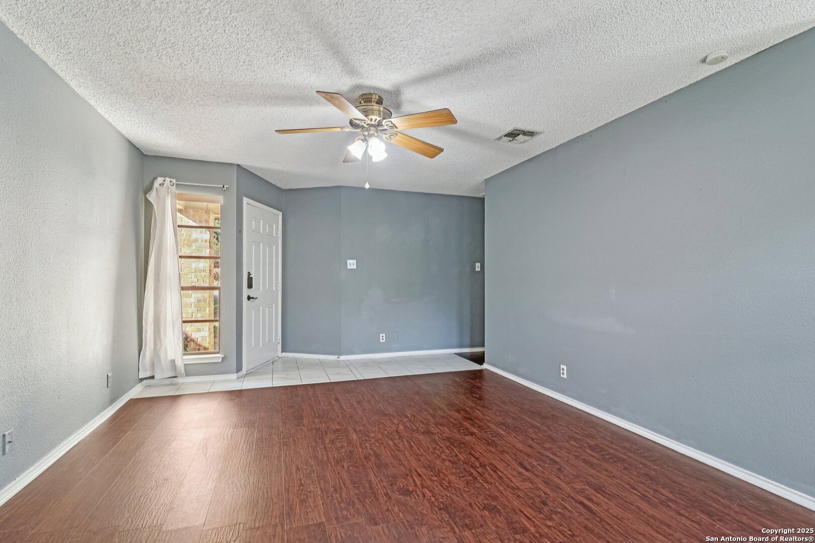 9334 Dover Ridge San Antonio, TX 78250 - Photo 12 of 39 an empty room with wooden floor chandelier fan and windows