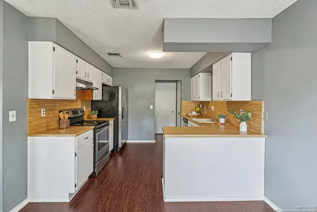 a kitchen with stainless steel appliances granite countertop a refrigerator a stove top oven a sink and dishwasher