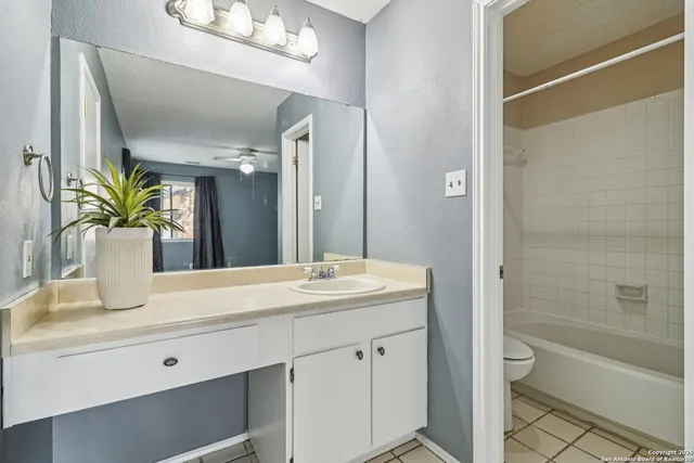 a bathroom with a granite countertop sink a toilet a large mirror and shower