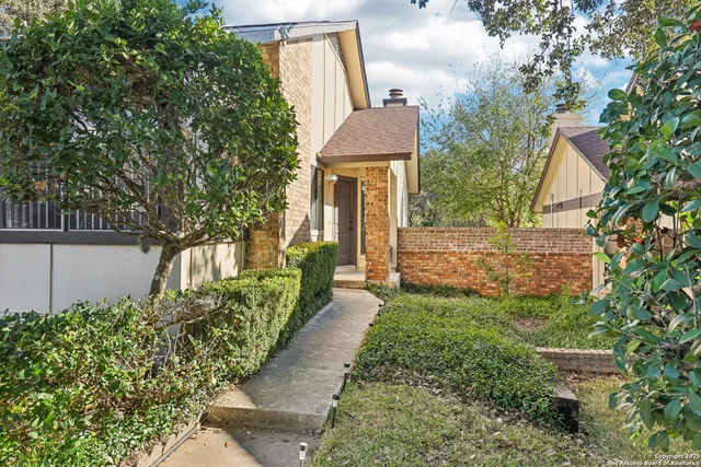 a view of a house with a small yard plants and large tree