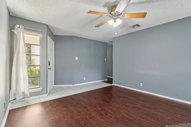 a view of an empty room with window and wooden floor