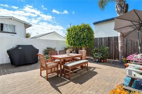 a patio with table and chairs and potted plants