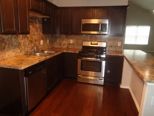 a kitchen with granite countertop a stove a microwave a sink and cabinets