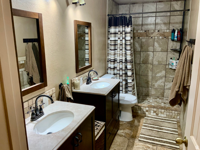 76 Highway 118 Monroe, UT 84754 - Photo 69 of 76 Bathroom featuring a shower stall, a textured wall, two vanities, and stone tile floors
