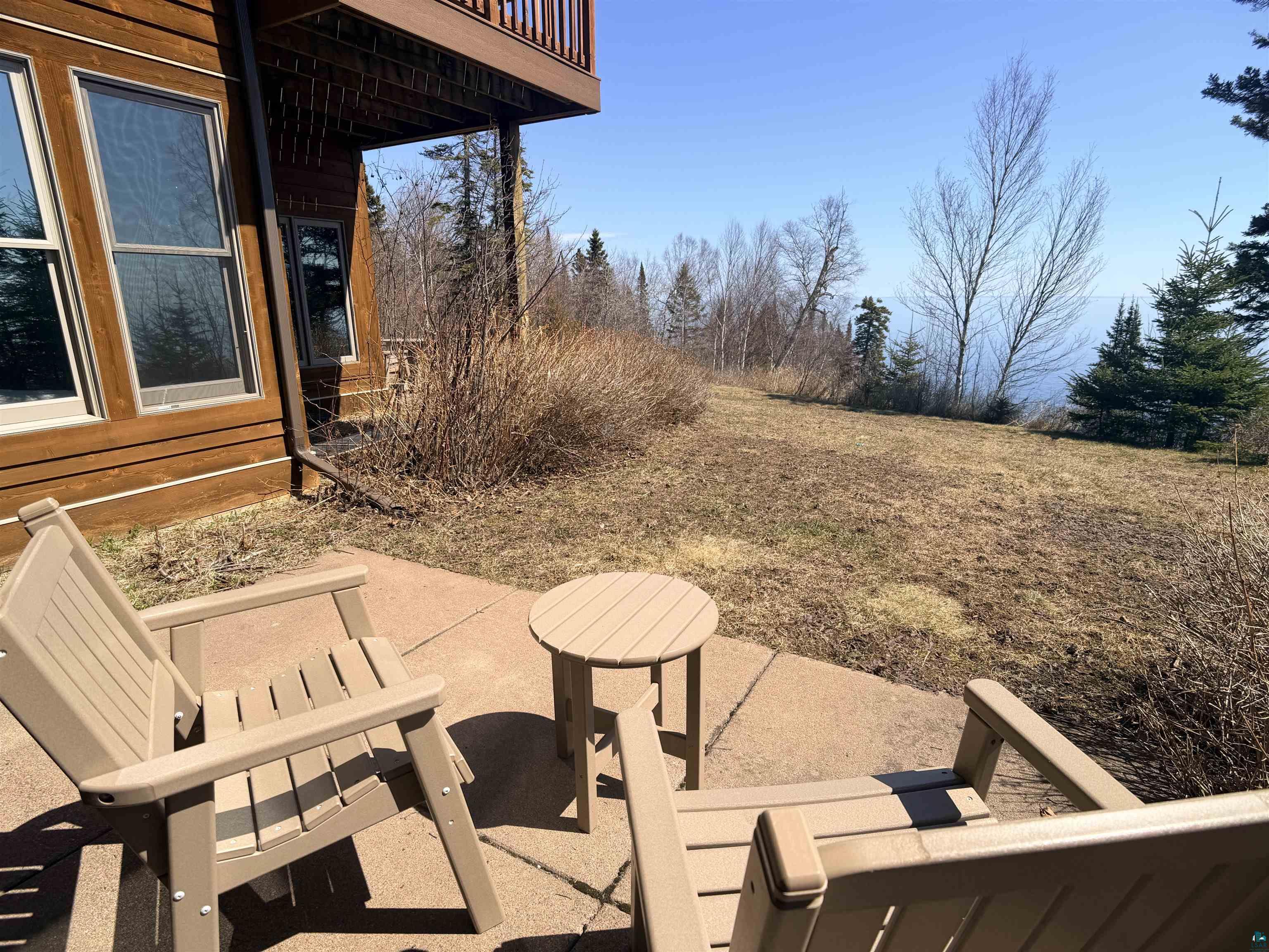 504-506 Poplar River Road, Unit 505 Lutsen, MN 55612 - Photo 38 of 39 Outdoor patio featuring concrete pavers, a natural hillside, mature evergreen trees, and a distant body of water