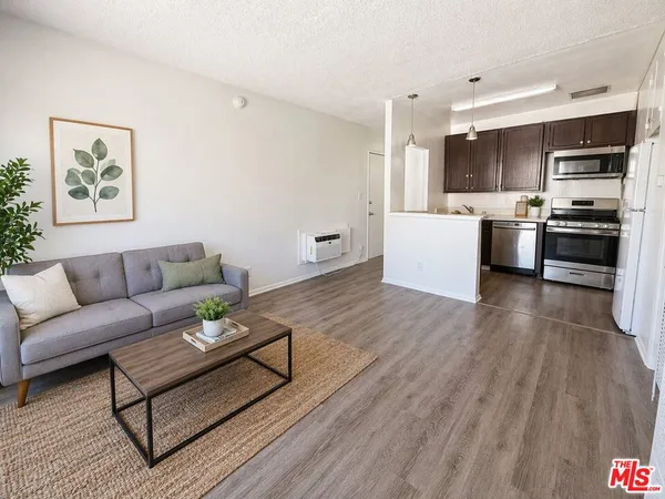 a living room with stainless steel appliances furniture and a kitchen view