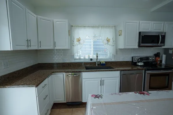 a kitchen with granite countertop white cabinets and a sink