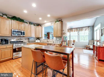 a kitchen with stainless steel appliances granite countertop a stove top oven a sink dishwasher a dining table and chairs with wooden floor