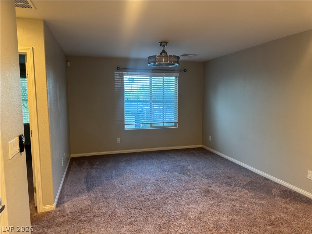55 Canopus Ridge Way Las Vegas, NV 89183 - Photo 38 of 53 Soft carpeting pairs with a wide window, creating a comfortable and inviting atmosphere.