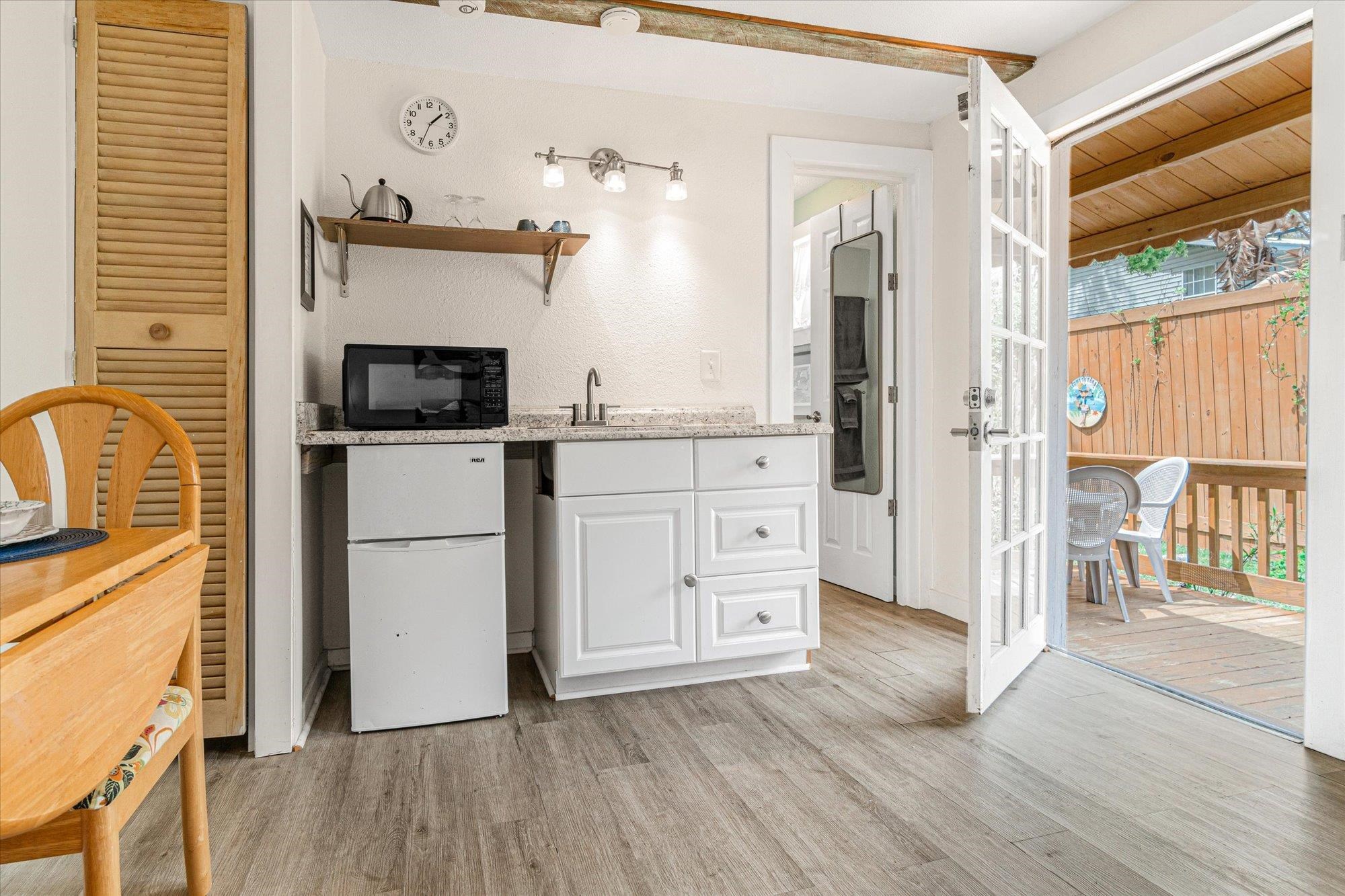 68 Kings Ferry Way St. Augustine, FL 32084 - Photo 41 of 52 Bar area with white cabinets, freestanding refrigerator, light wood finished floors, black microwave, and open shelves