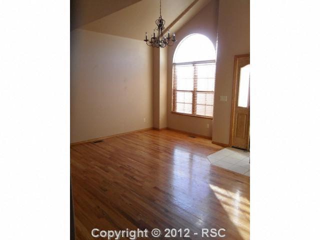 12336 Snaffle Bit Road Peyton, CO 80831 - Photo 2 of 8 Formal living room has vaulted ceilings and hardwood floors. The entry is tile and provides easy access to a coat closet.