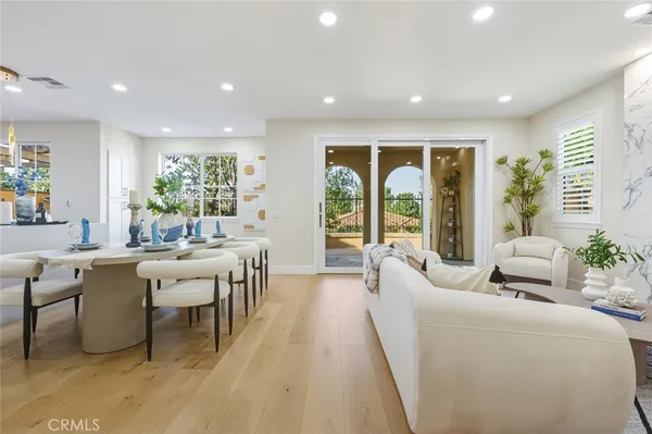 a living room with furniture two large window and wooden floor