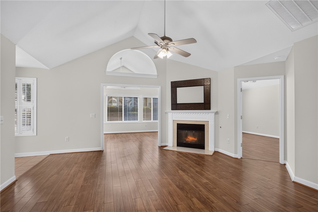 134 Life Style Lane Anderson, SC 29621 - Photo 8 of 44 A living area features soaring vaulted ceilings and rich hardwood flooring, with a cozy fireplace providing warmth and ambiance.