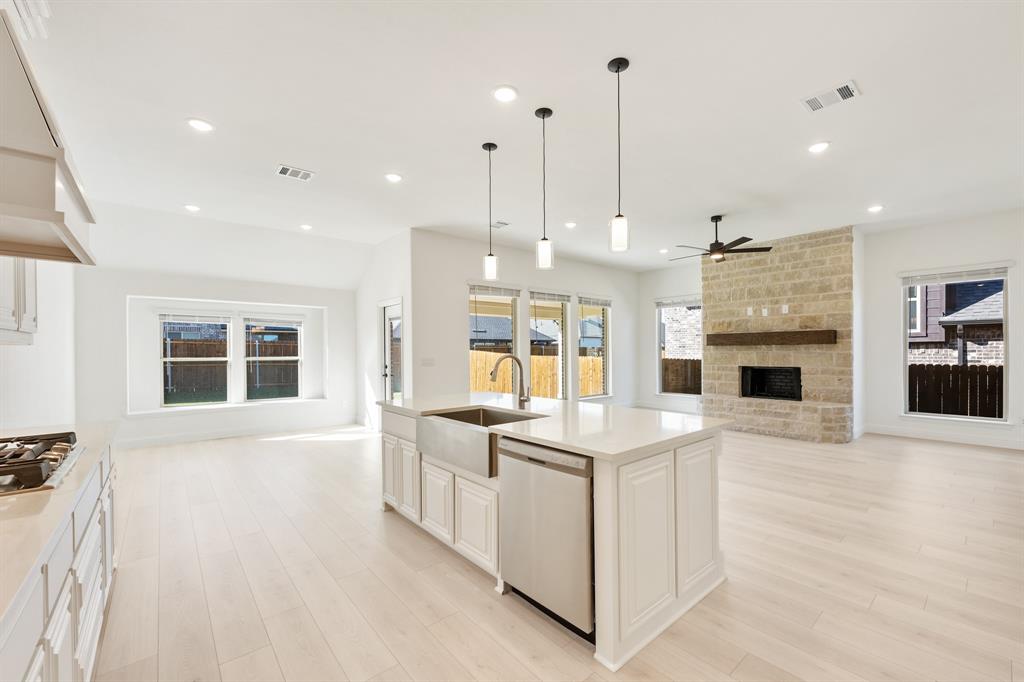 2005 Ambergate Drive Anna, TX 75409 - Photo 22 of 35 a view of a kitchen with kitchen island stainless steel appliances a stove a sink dishwasher and a fireplace with wooden floor