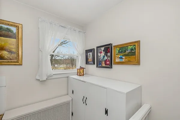 a view of a hallway with paintings on the wall and a window