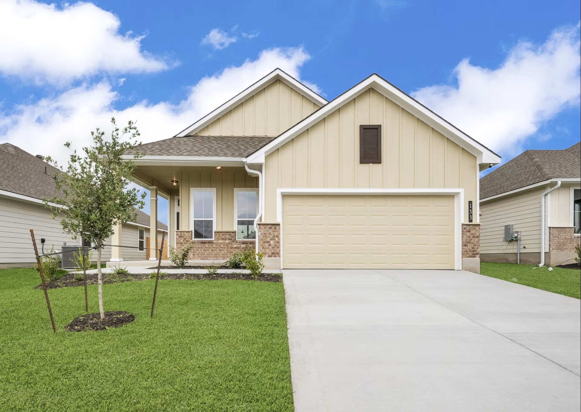 Craftsman inspired home featuring board and batten siding, covered porch, a front yard, concrete driveway, and roof with shingles