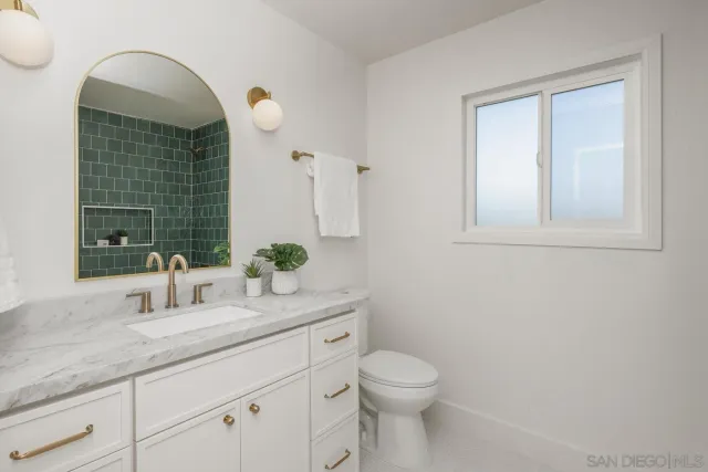 a bathroom with a granite countertop sink a toilet and mirror