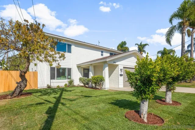 a front view of a house with a yard and trees