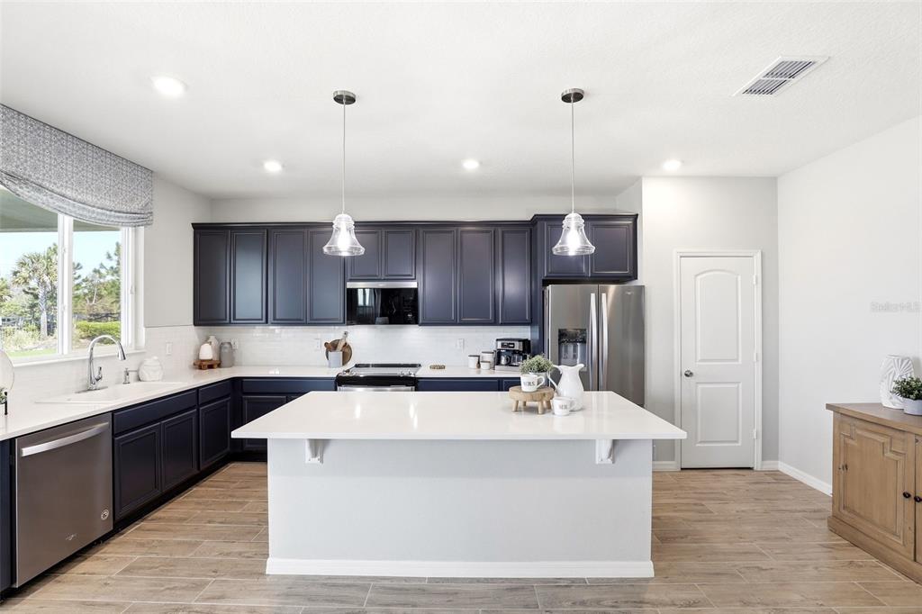 740 Rioja Drive Minneola, FL 34715 - Photo 12 of 33 a large white kitchen with a sink and dishwasher a stove top oven with wooden floor