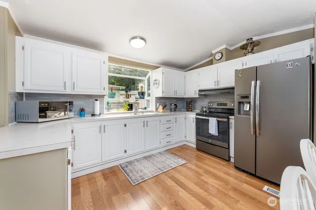 a kitchen with stainless steel appliances white cabinets a sink a stove a refrigerator and cabinets