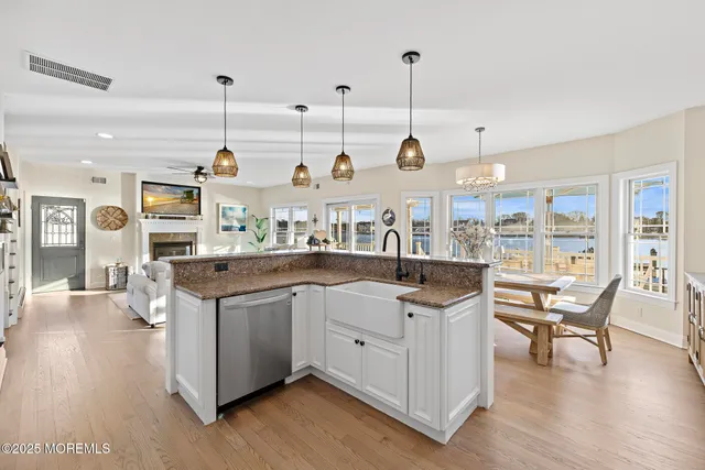 a open kitchen with stainless steel appliances granite countertop a stove and chairs with wooden floors