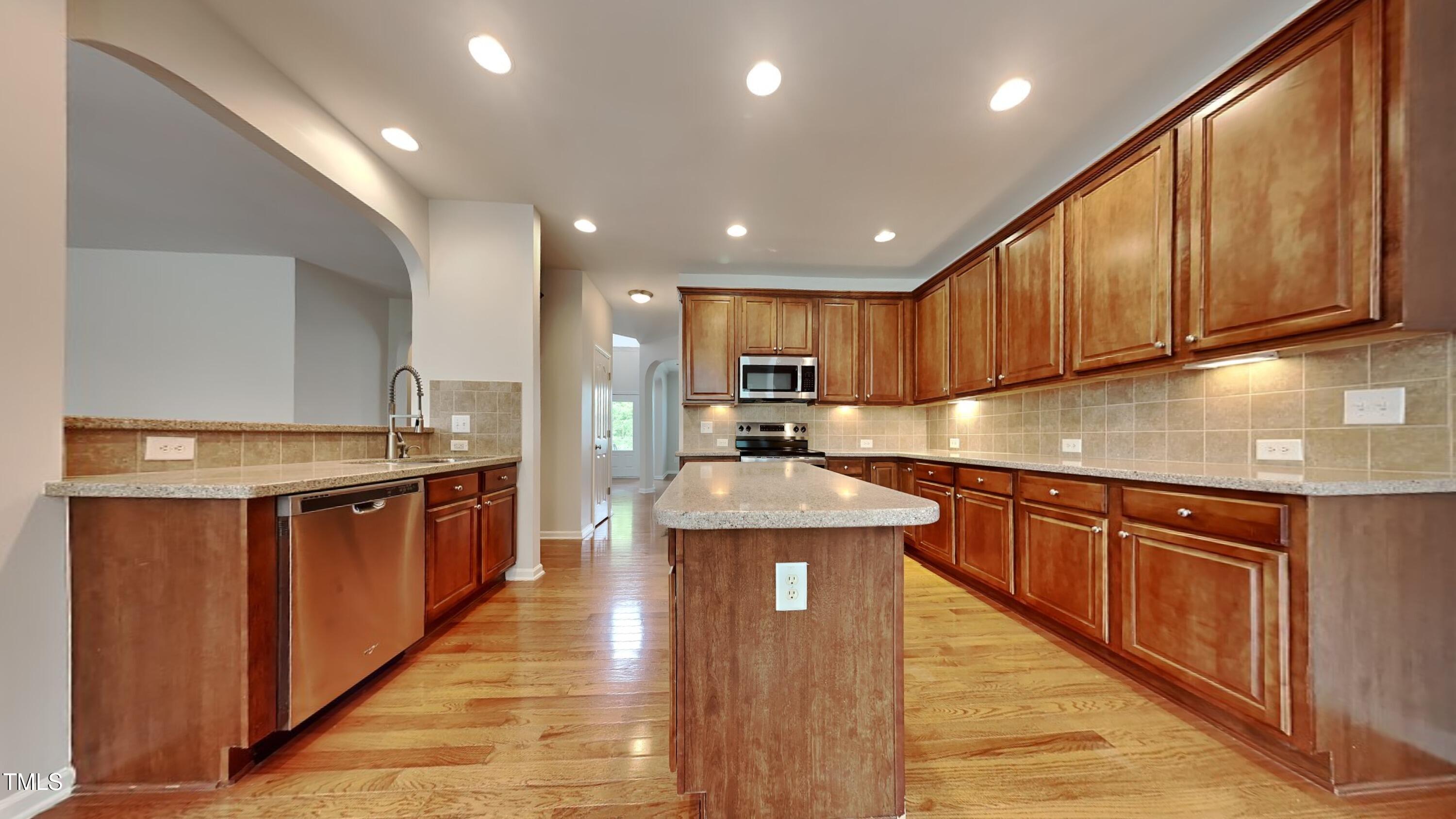 9037 Linslade Way Wake Forest, NC 27587 - Photo 4 of 16 a kitchen with stainless steel appliances granite countertop wooden cabinets a sink and dishwasher a stove top oven with wooden floor