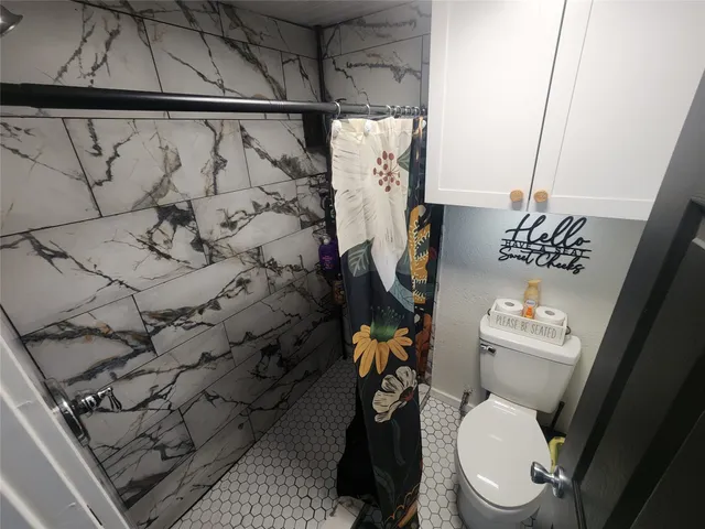a white toilet sitting next to a shower curtain