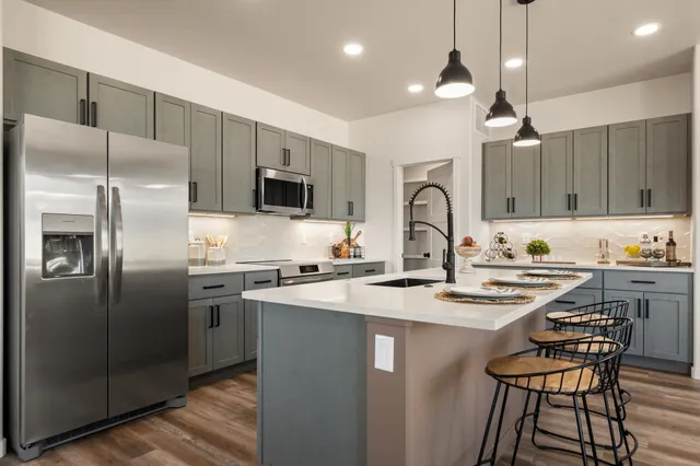 a kitchen with stainless steel appliances granite countertop a sink a stove a refrigerator cabinets a dining table and chairs