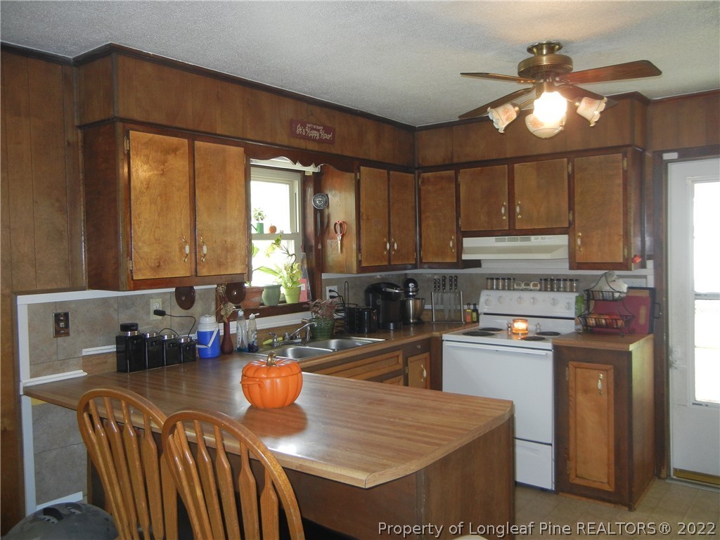 648 Pleasant Loop Fayetteville, NC 28311 - Photo 6 of 20 a kitchen with stainless steel appliances granite countertop a stove a refrigerator a sink a dining table and chairs with wooden floor