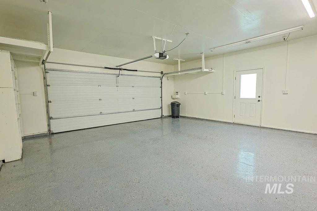 640 Morrison Street Twin Falls, ID 83301 - Photo 26 of 30 Spacious garage featuring a light gray epoxy floor, white paneled garage door, and a pedestrian door with a window