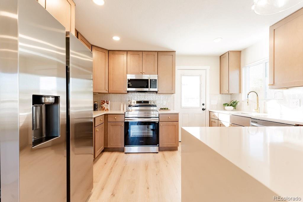 1105 South Raleigh Street Denver, CO 80219 - Photo 6 of 23 a kitchen with stainless steel appliances granite countertop a refrigerator a stove and a sink with wooden floor